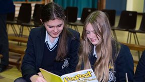 Two school girls read Respect magazine. 