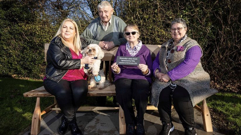 Full of chat….Delighted members of the Moneydig community gather to try out the new chatty bench funded by The Housing Executive and celebrate winning two Best kept Council Amenity Awards. Seated (left to right) Patricia McQuillan MBE, Secretary, Moneydig Rural Network, Thor the dog, Jean Henderson, Housing Executive tenant and Mary Gibson, Chair of Moneydig Rural Network. Standing is Ian Henderson, Housing Executive tenant. Ian and Jean Henderson have planted all the flowers in Moneydig