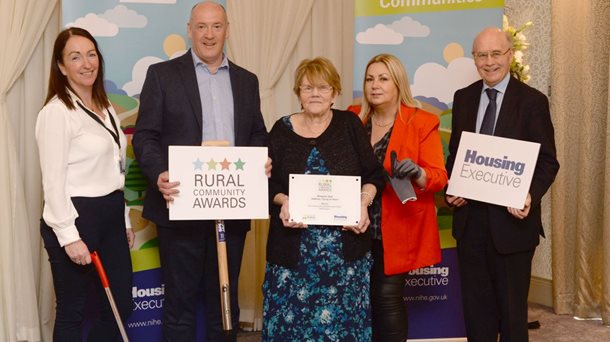 Margaret Reid (middle), Chairperson of Ballintoy Young at Heart proudly holds the plaque awarded to her as the  winner of the Housing Executive’s coveted Rural Community Champion Award 2023, north region. Congratulating Margaret at the annual awards ceremony are, from left, Noeleen Connolly, Housing Executive Team Leader, Ballymoney and Ballycastle, Colm McDaid, Supporting Communities, Patricia McQuillan MBE, Rural Residents Forum and Frank O’Connor, Housing Executive North Regional Manager.