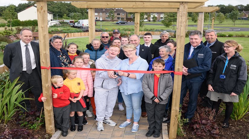 Adam Anderson cuts the ribbon to officially open Ballykeel 2 Community Garden watched by local residents and supporters.