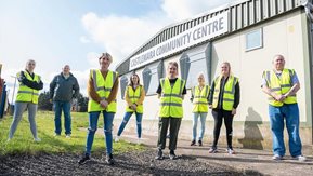 8 people pose outside a building