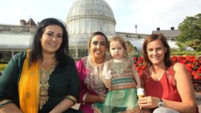 Three women and a child eat ice cream in Belfast's Botanic Gardens.