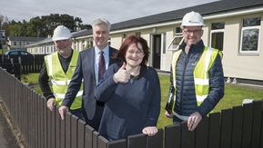 Smiling woman with workmen in front of bungalow