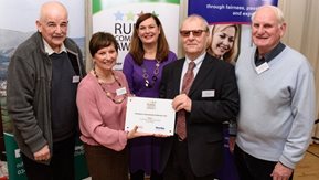 A small group of men and women pose with an award certificate.