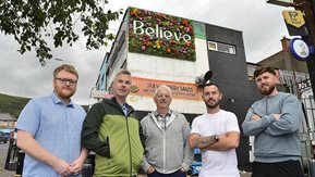 Five men stand in front of the new wall art.