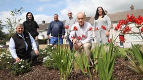 Group of people admire a flower bed.