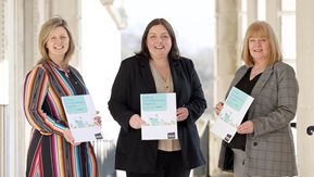 Three women holding the new strategy document
