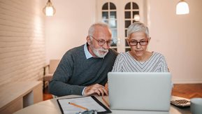 An older man and woman at a laptop computer.