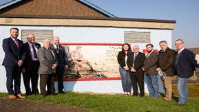 A group of people stand in front of a mural.