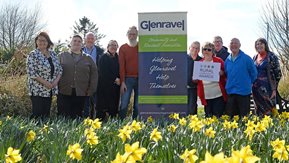 Ten people beside Glenravel sign ,with daffodils in foreground 
