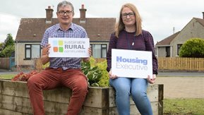 A man and woman sit on a wall outside a home in Lislagan.