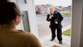 A woman answers the door to an unknown man.