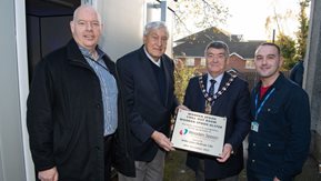 Four men pose with plaque