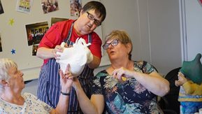 Two women examine a ceramic figurine.