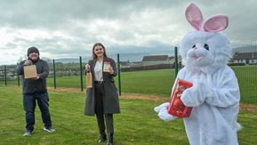 A man and woman hold Easter eggs while posing with the Easter bunny