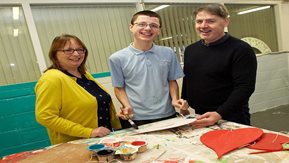 Two adults and a youth with artwork.