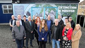 A group of people pose in front of a mural