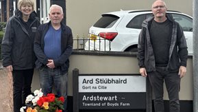 Anne-Marie, Keith and Jonny are outdoors, standing by a colourful flower arrangement.