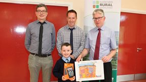 Three men with a child holding his prize and winning artwork.