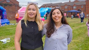 Two women, with a bouncy castle in background,