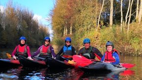 Five canoeists pose on river