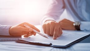 Two people examine the contents of a clipboard.