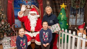 Two girls and HE employee pose with Santa