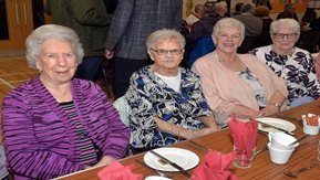 Four older people sit at a table.