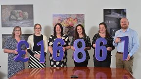 Six people hold numbers showing the £16,634 raised