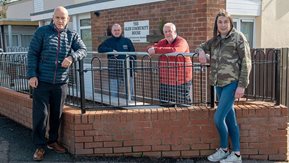 Four people stand outside a building