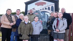 Staff and pupils pose in front of the new mural.