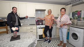 Two women and a man in new kitchen in a Housing Executive home.