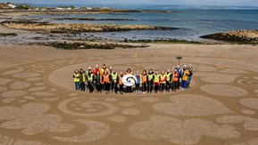 Volunteers pose inside the beach art they created