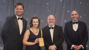 Three men and a woman pose with award.