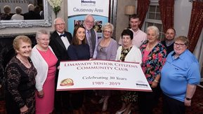 A small group of people pose with an over sized cheque.