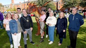 A group of people outdoors in the sun with a large "dragon".