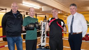 A group of men pose in a boxing ring of a boxing club