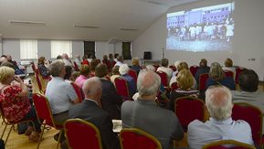 A group of people watch a video projected on to a screen.