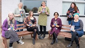 A group of women pose with a book