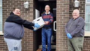 Two men present a package to a resident
