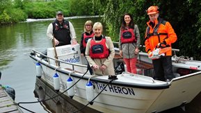 Several people in safety gear stand on a river boat.