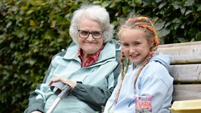 An older woman sits with a young girl.