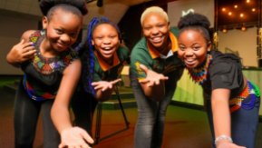three women smile and hold their hands out to the camera at an event to celebrate diversity 