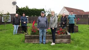 People stand in front of raised flower beds