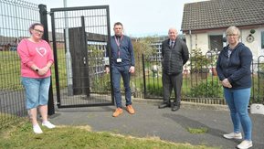 Four people pose by a security gate