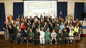 A large group of children hold up their certificates.