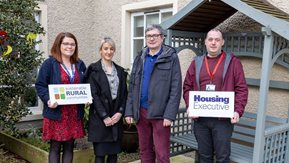 Four people pose with sustainable rural communities placards 