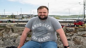 A man sits on a wall in Rathlin island