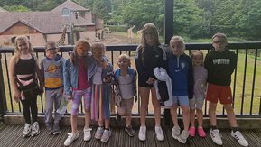 Children pose with giraffes in background.