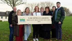 A group of eight people hold a large sign reading "Larchfield Gardens - Best kept medium housing area 2025".